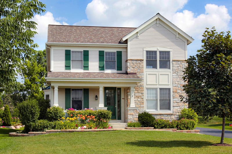 A two-story house with a stone front and a covered porch